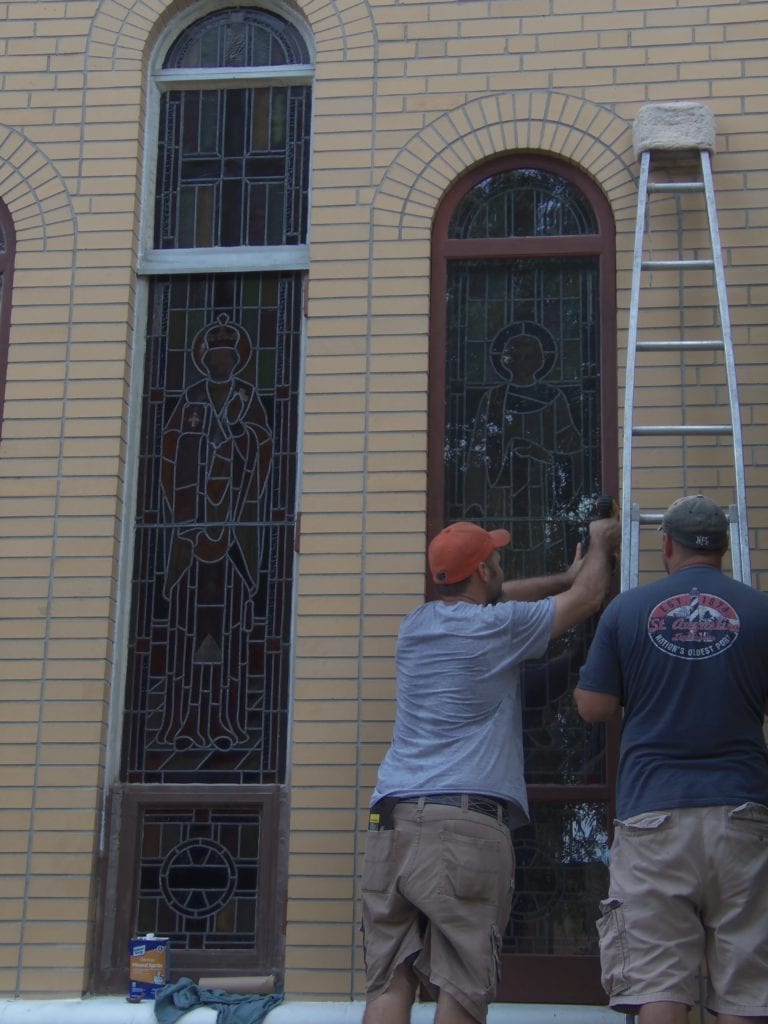 Stained glass church window being installed at a church